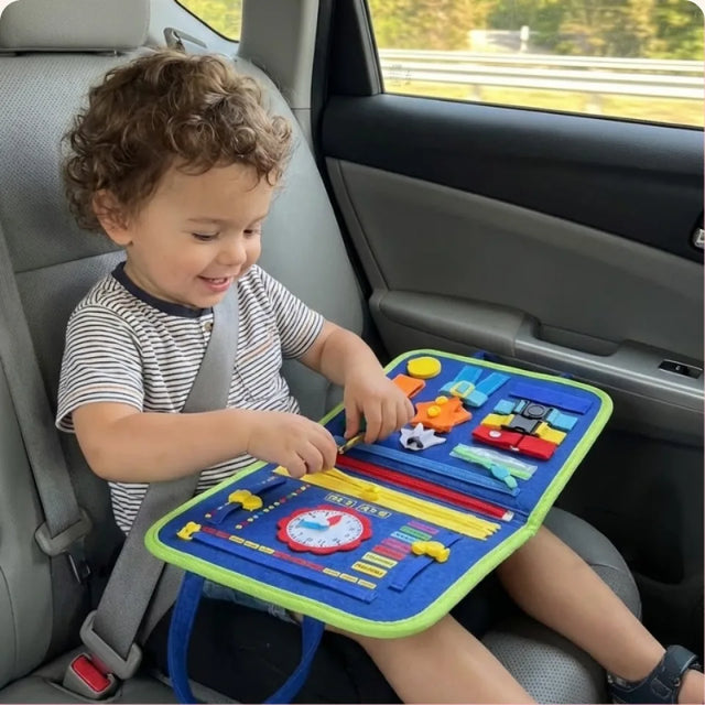 Toddler playing with the Busy Board in a car seat